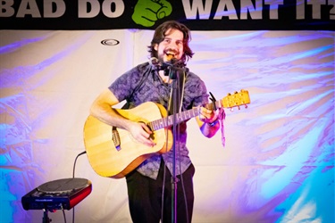 A performer singing and playing a guitar